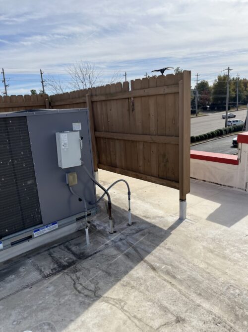 Rooftop HVAC unit beside wooden privacy fence