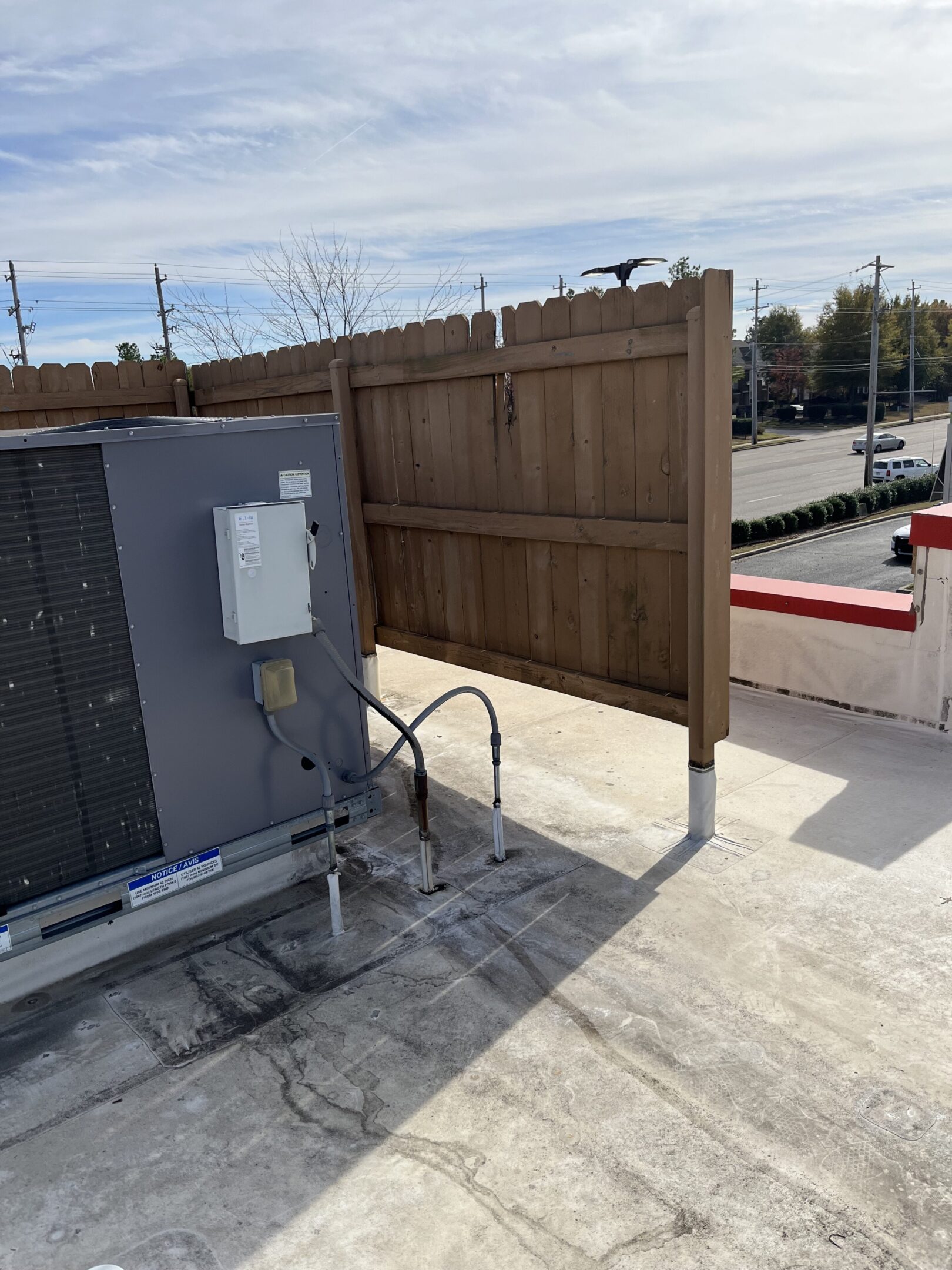 Rooftop HVAC unit beside wooden privacy fence