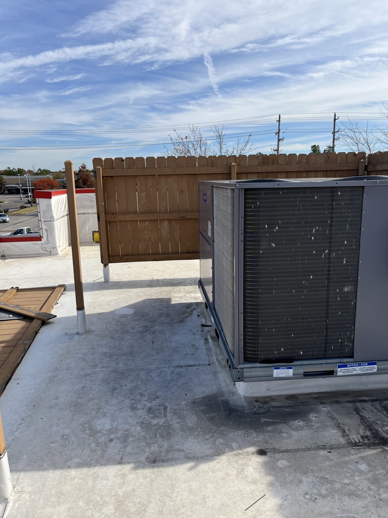 Rooftop HVAC unit next to wooden fence